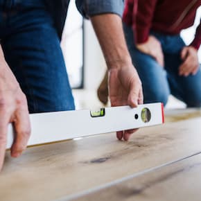 Close-up of a person using a spirit level to check the evenness of a wooden floor