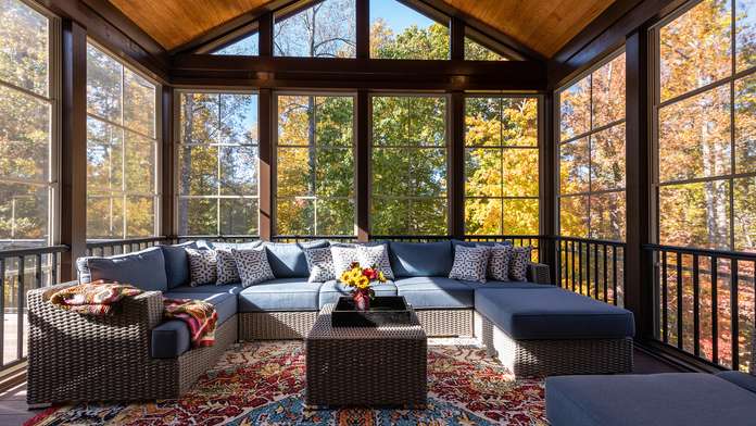 A bright sunroom with plush couches and a decorative rug, perfect for relaxation and enjoying natural light.